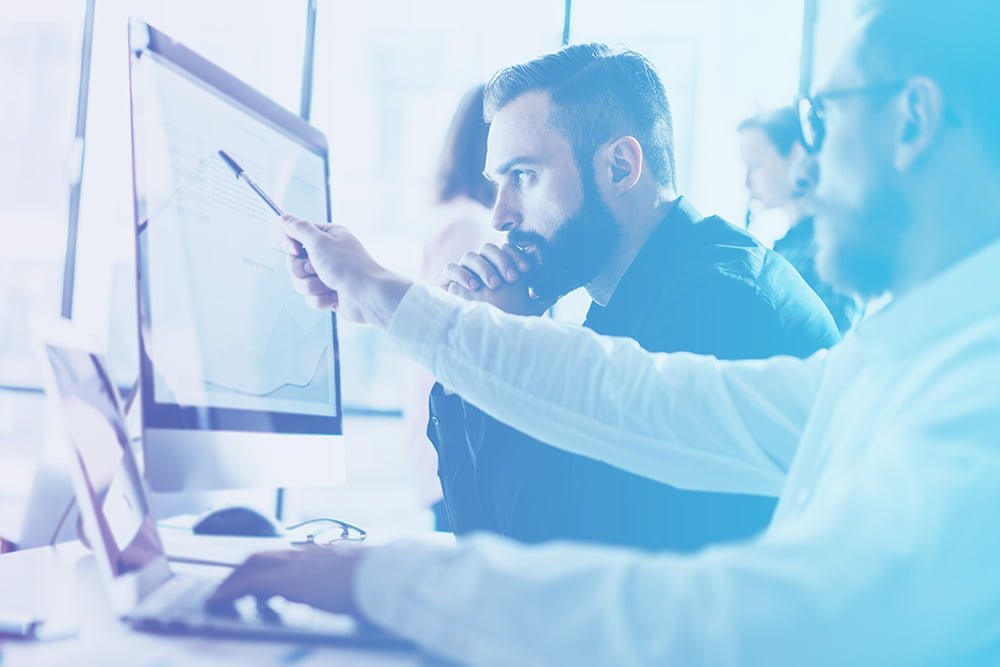 Two individuals engrossed in their work, collaborating on a computer screen.